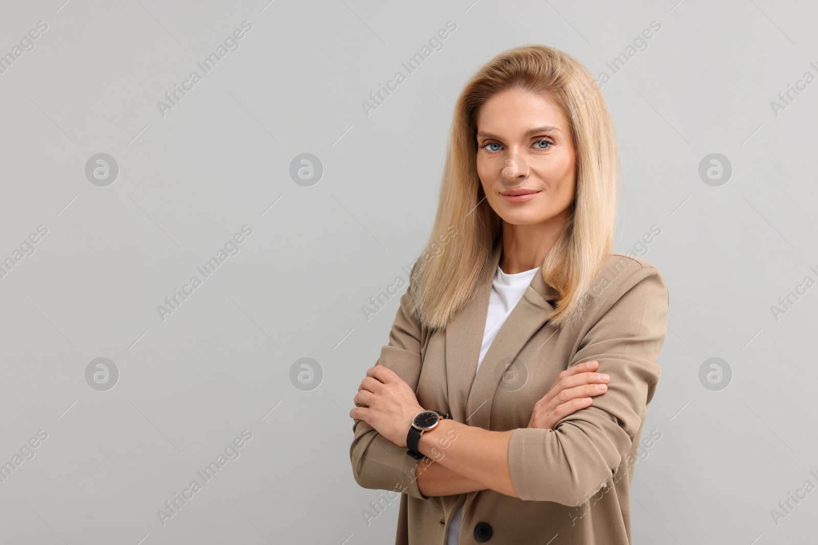 Photo of Portrait of beautiful middle aged businesswoman with crossed arms on light grey background. Space for text