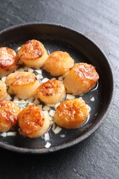Photo of Delicious fried scallops in dish on dark gray textured table, above view