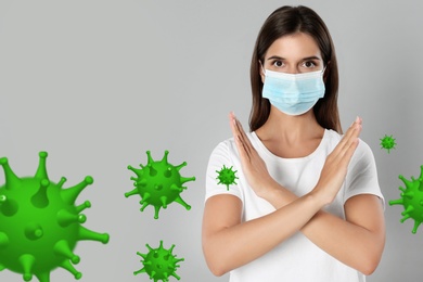 Image of Stop Covid-19 outbreak. Woman wearing medical mask surrounded by virus on light background