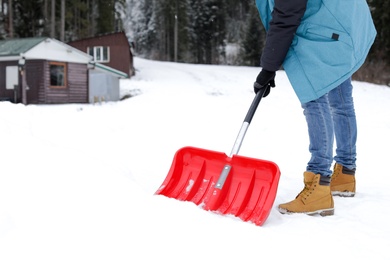 Man removing snow with shovel near house. Space for text