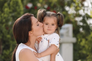 Photo of Beautiful mother kissing her cute daughter outdoors