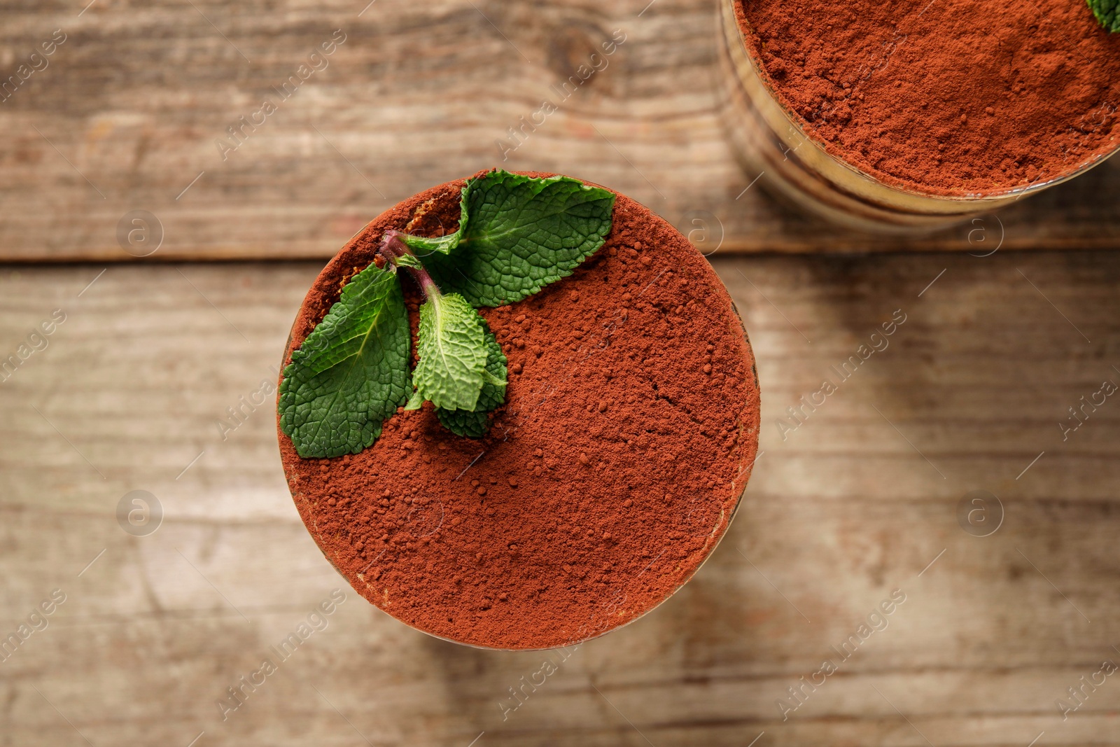 Photo of Tasty tiramisu and mint in glasses on wooden table, top view