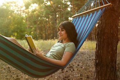 Photo of Woman with book resting in comfortable hammock outdoors