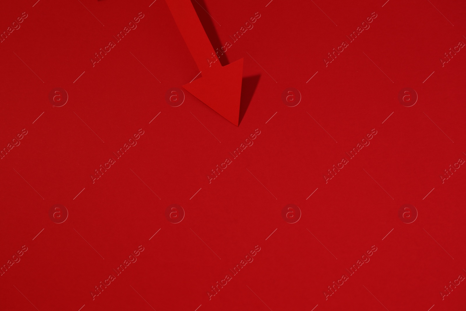 Photo of One paper arrow on red background, top view. Space for text