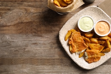 Photo of Plate with British traditional fish and potato chips on wooden background, top view. Space for text