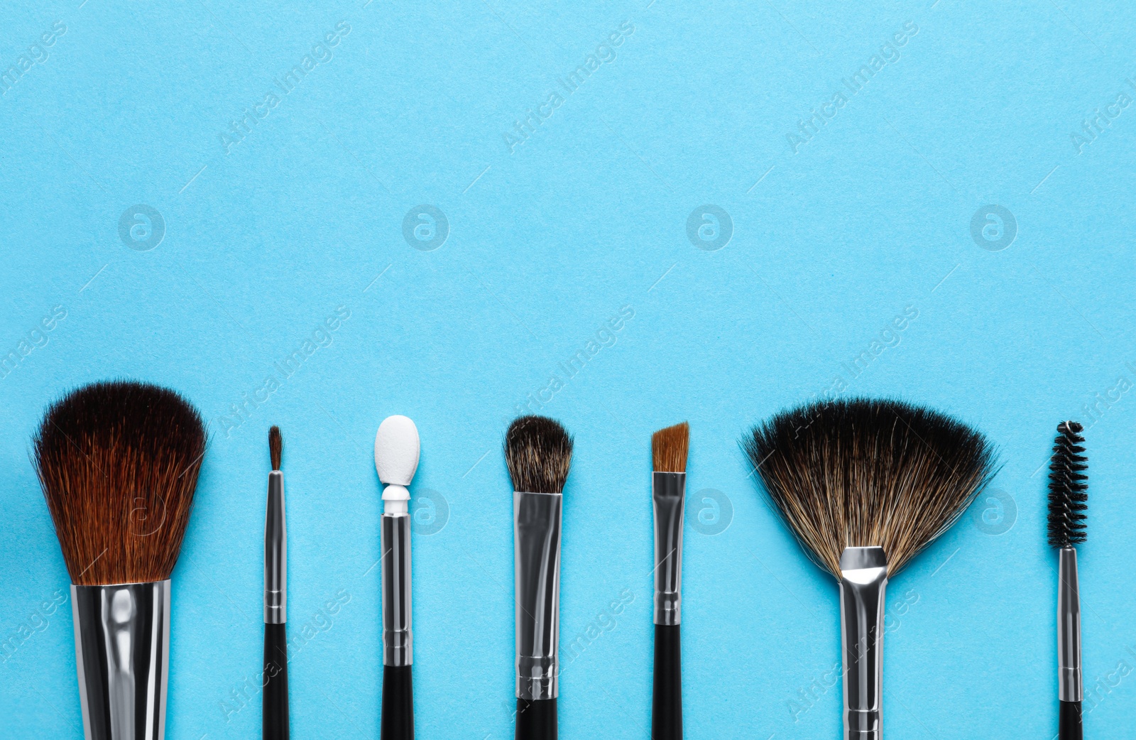 Photo of Set of makeup brushes on light blue background, flat lay. Space for text