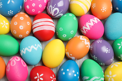 Photo of Many bright Easter eggs on wooden background, top view