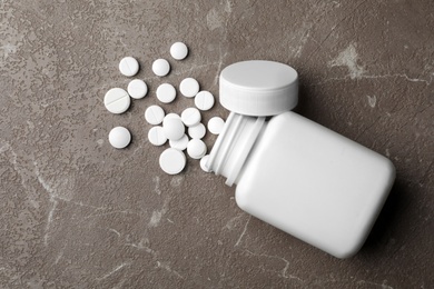 Bottle with different pills on table, flat lay