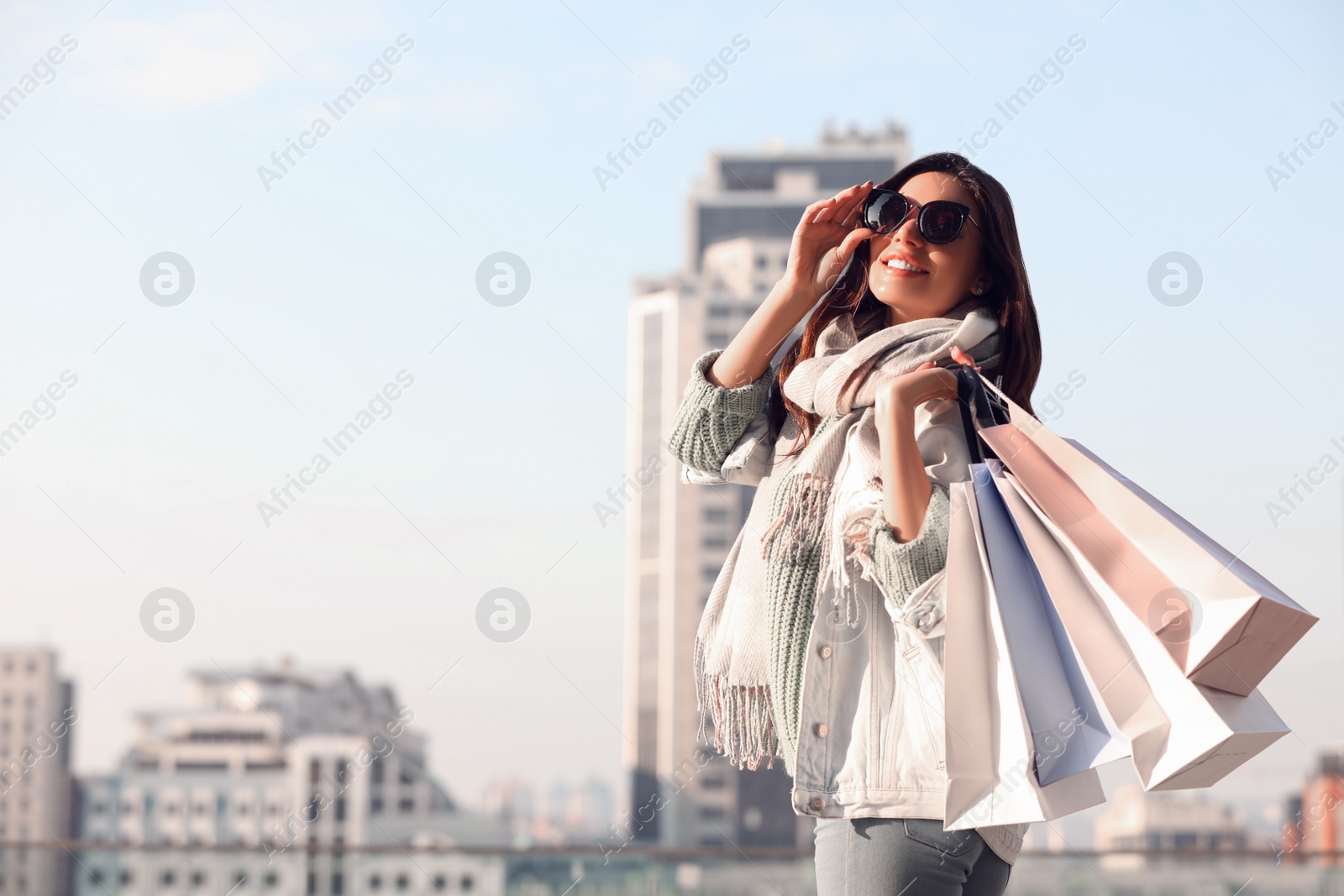 Photo of Beautiful young woman with shopping bags on city street