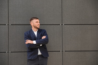 Portrait of handsome young man leaning to wall outdoors, space for text