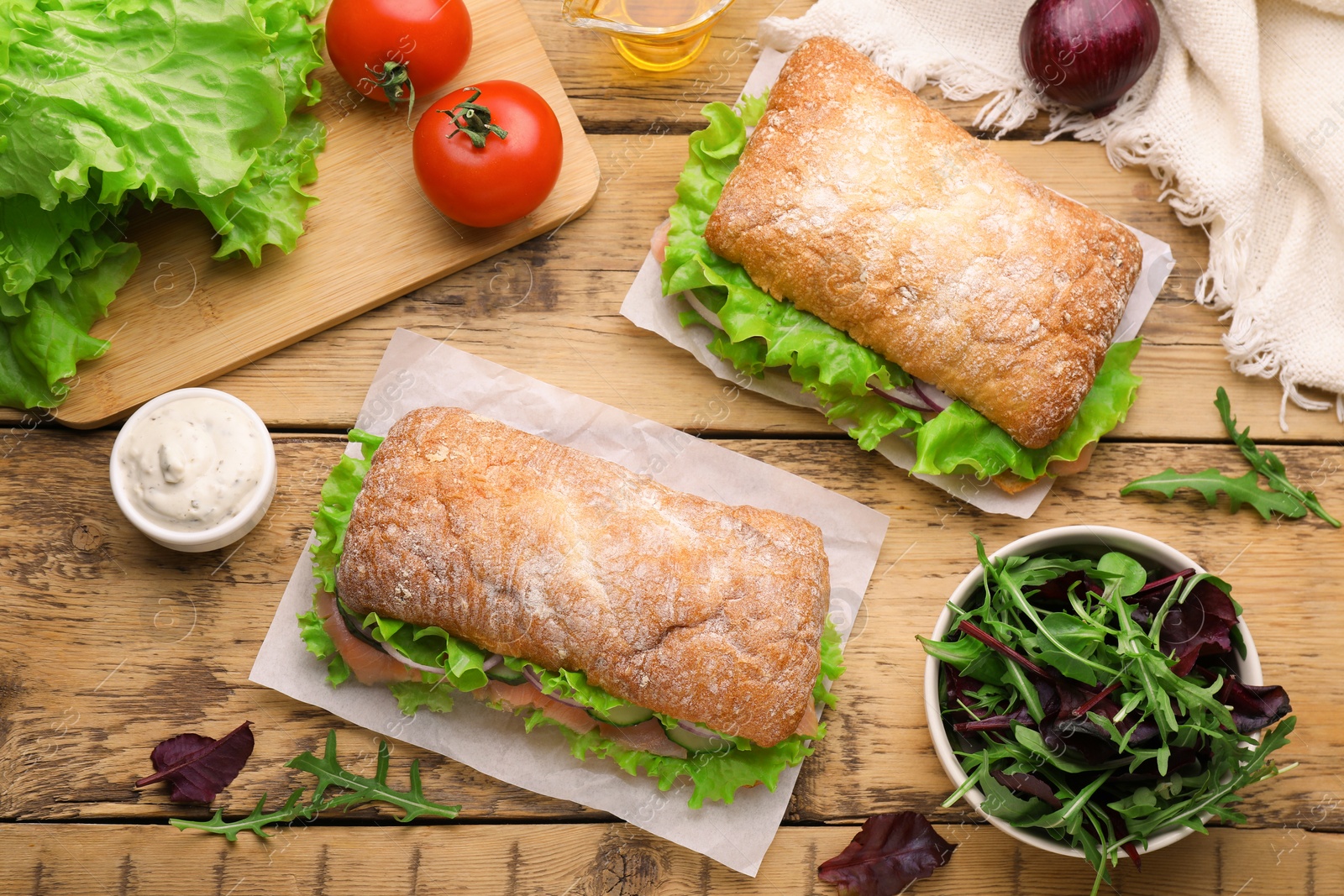 Photo of Delicious sandwiches with fresh vegetables and salmon on wooden table, flat lay