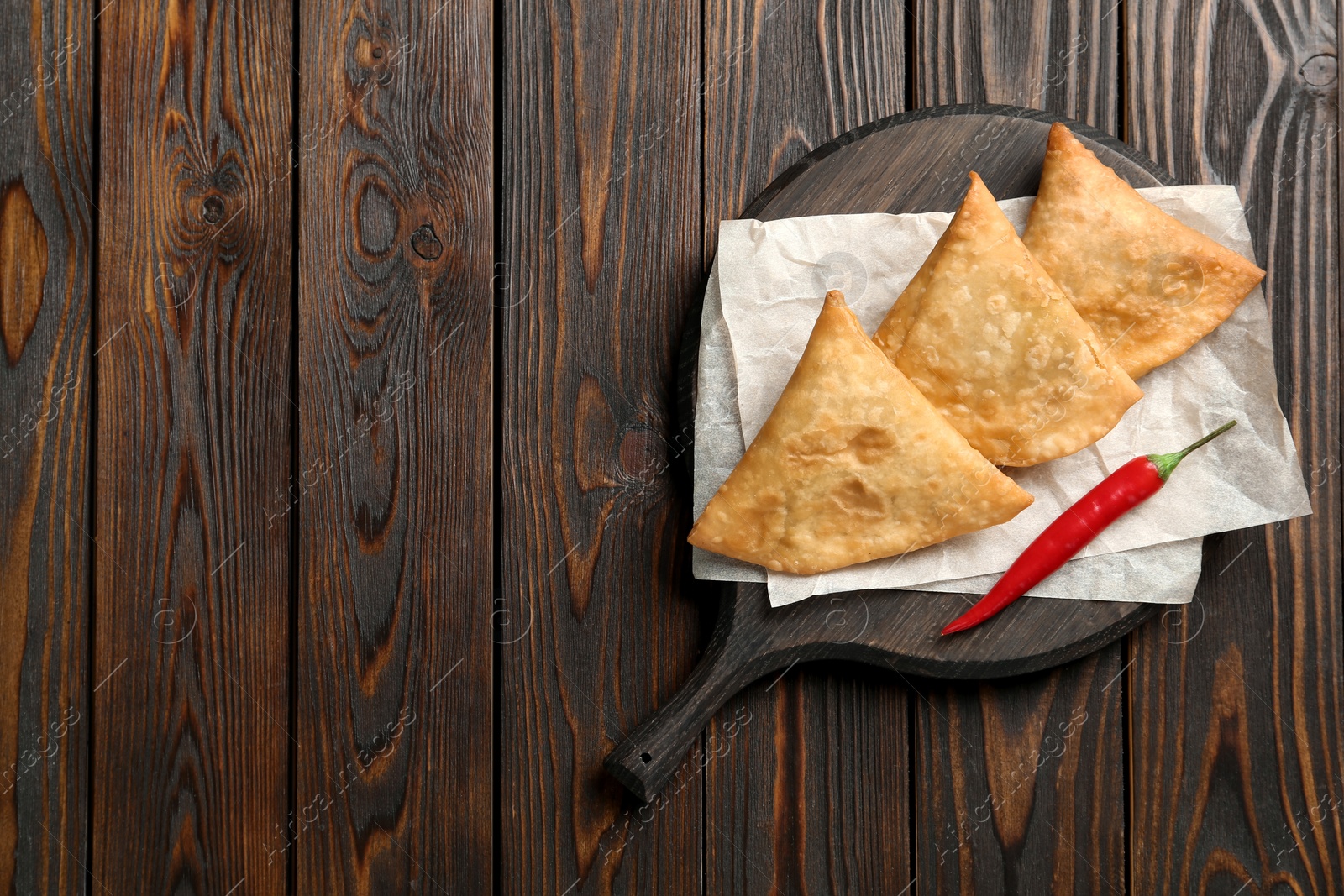 Photo of Fresh delicious crispy samosas served on wooden table, top view. Space for text