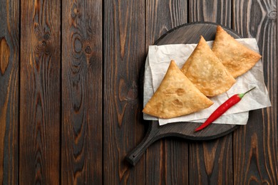 Photo of Fresh delicious crispy samosas served on wooden table, top view. Space for text