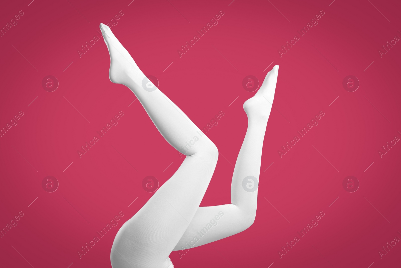 Photo of Woman wearing white tights on crimson background, closeup of legs