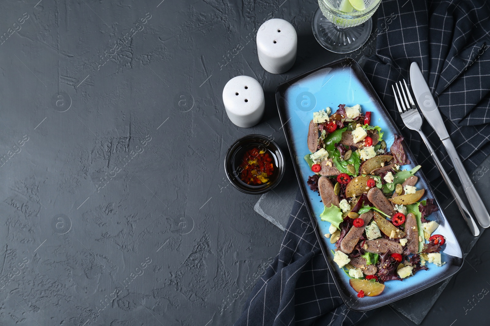 Photo of Delicious salad with beef tongue and cheese served on black textured table, flat lay. Space for text