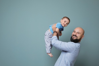 Portrait of dad and his little son on color background