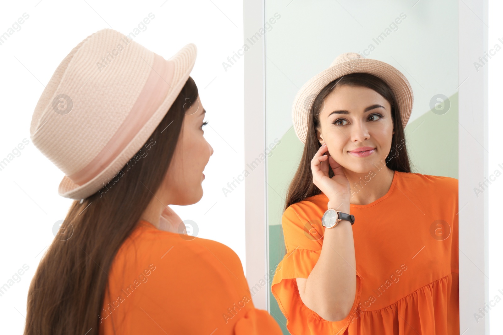 Photo of Young woman looking at her reflection in mirror on white background