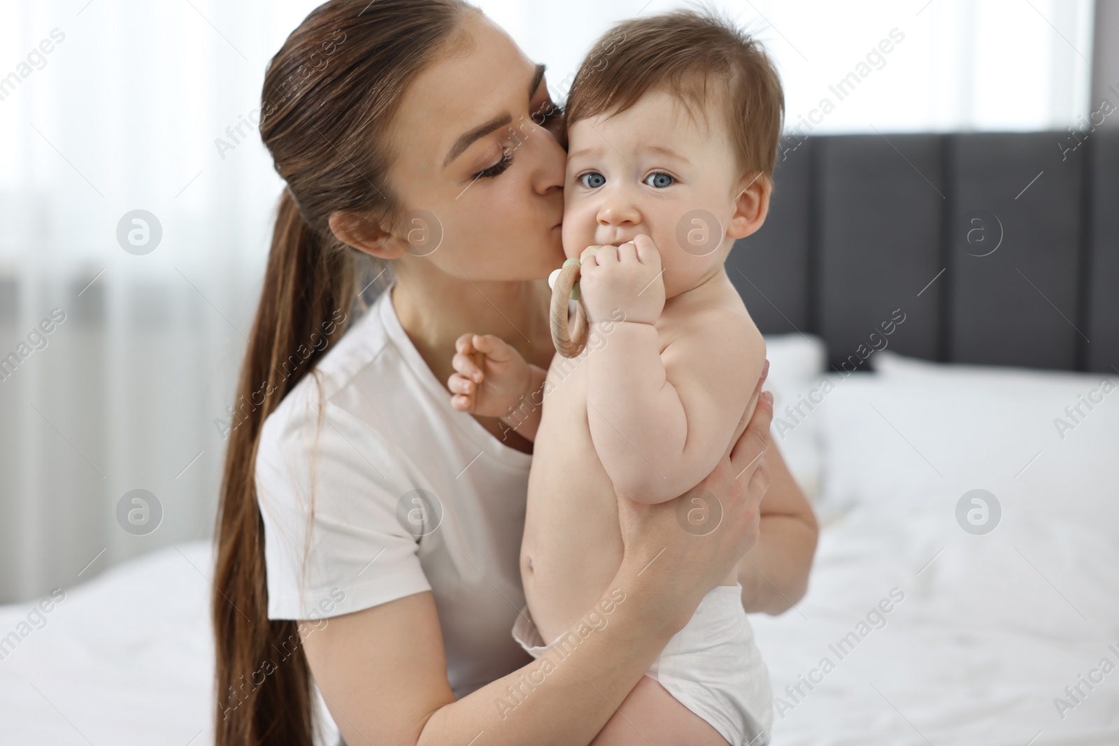 Photo of Mother kissing with her baby on bed at home