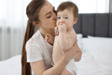 Mother kissing with her baby on bed at home