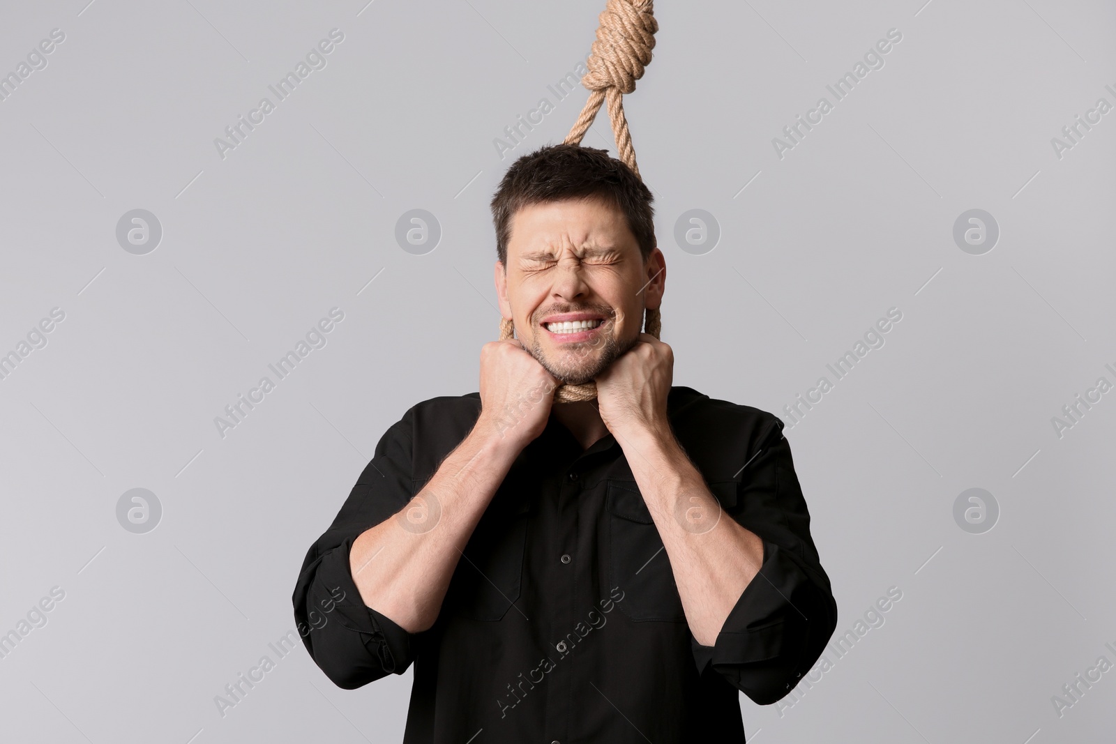 Photo of Depressed man with rope noose on neck against light background