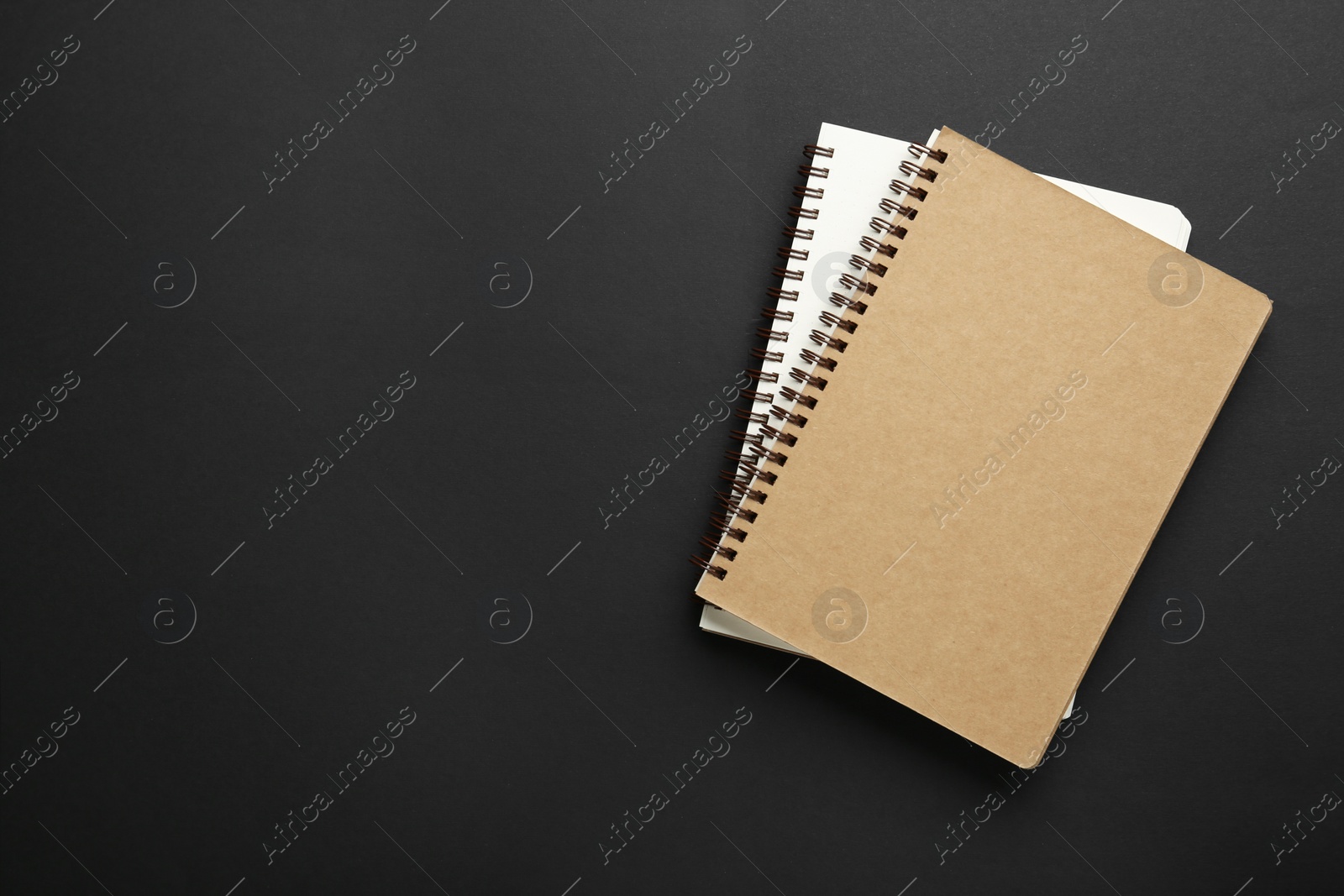 Photo of Notebooks on black background, top view. Space for text