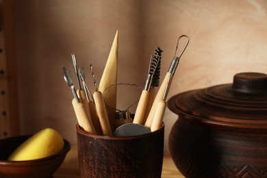 Photo of Set of different crafting tools and clay dishes on table in workshop
