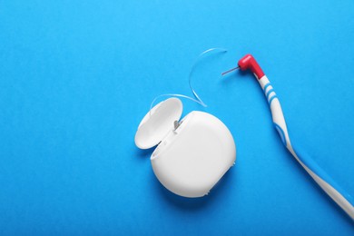 Photo of Container with dental floss and toothbrush on light blue background, flat lay. Space for text