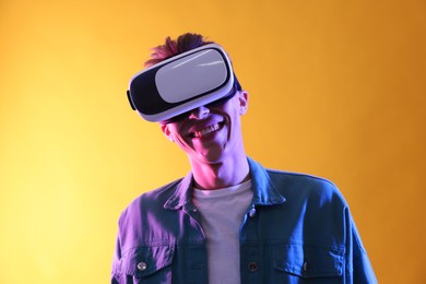 Photo of Young man with virtual reality headset on yellow background