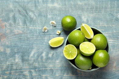 Bowl with fresh ripe limes on wooden background, top view