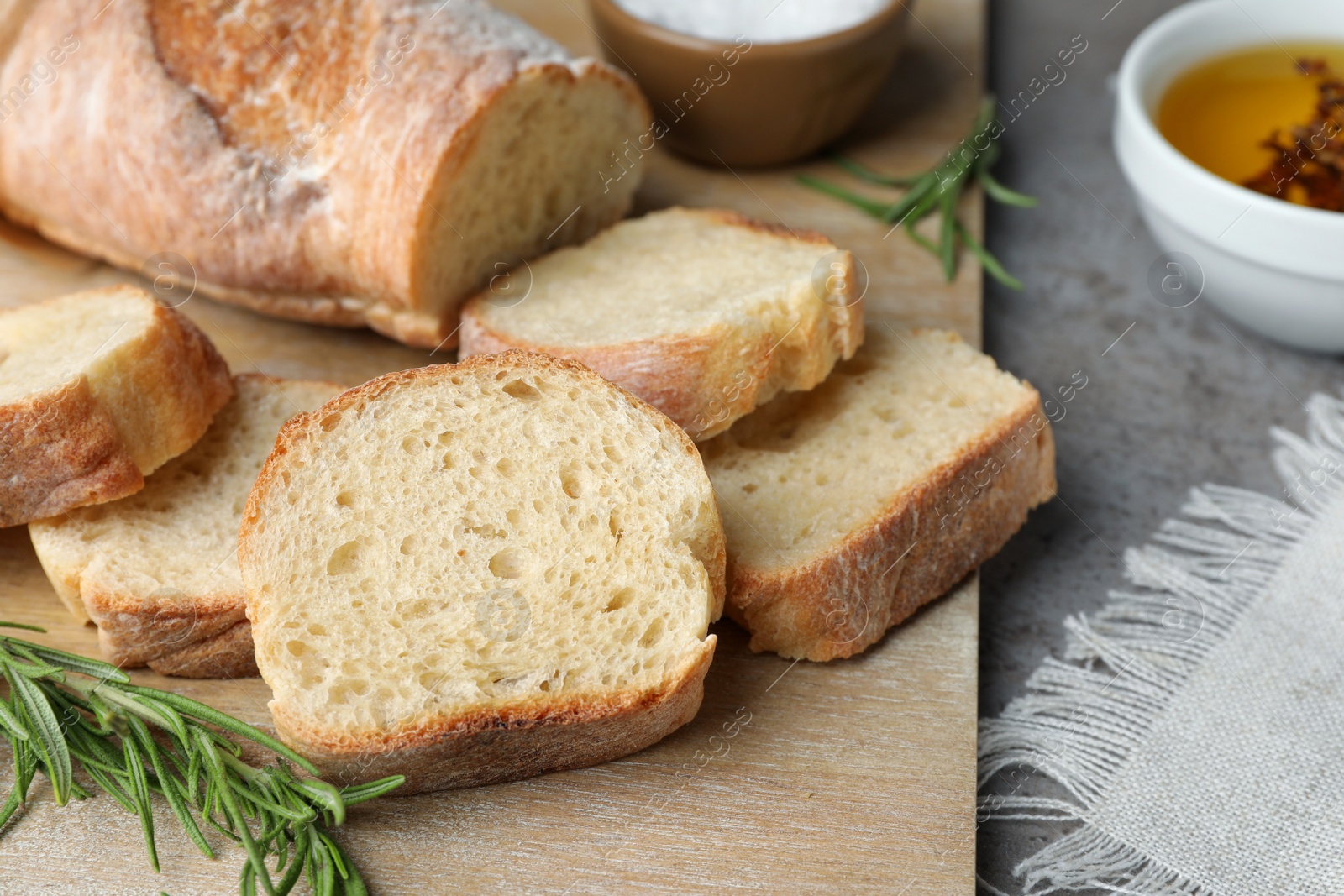 Photo of Fresh crispy baguette on grey table, closeup