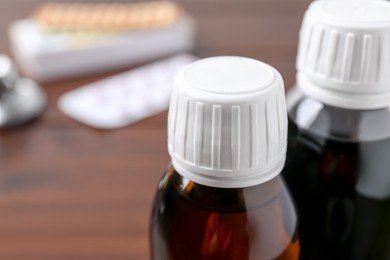 Photo of Bottles of syrup on wooden table, closeup with space for text. Cold medicine