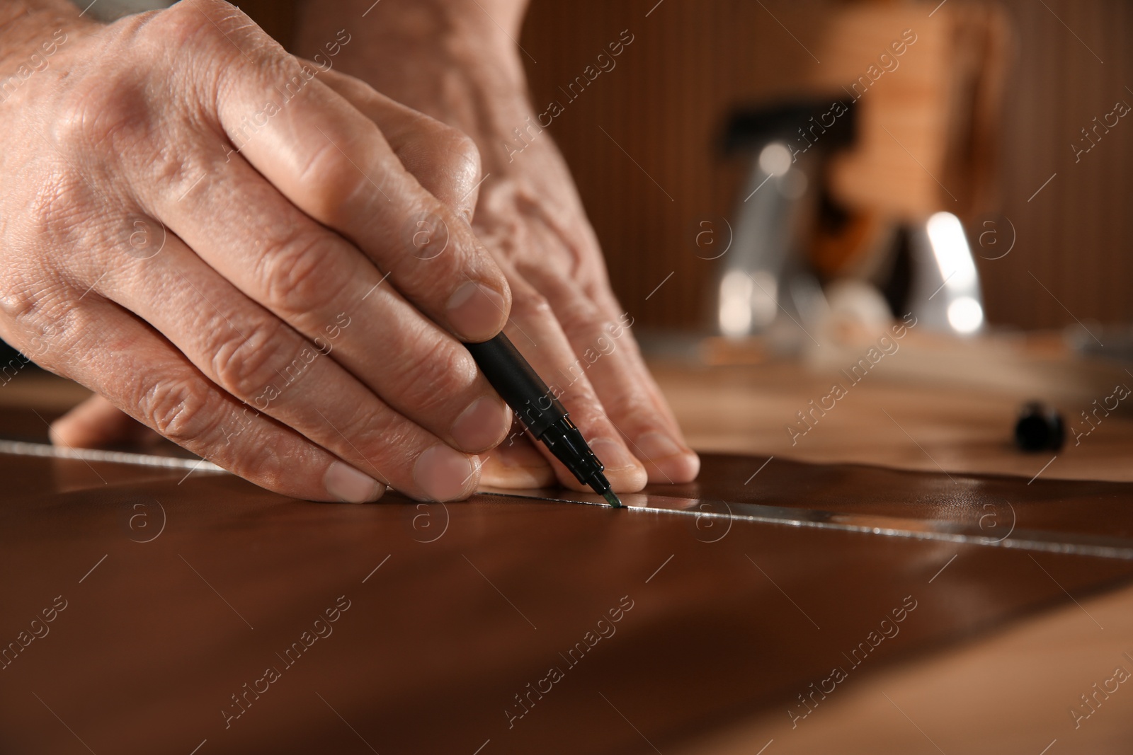 Photo of Man working with piece of leather in workshop, closeup