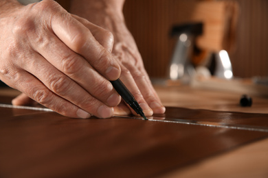 Man working with piece of leather in workshop, closeup