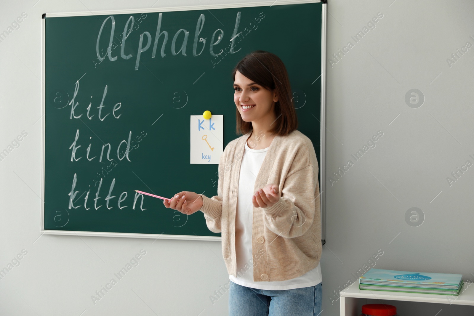 Photo of Happy female English teacher giving lesson indoors. Early childhood education