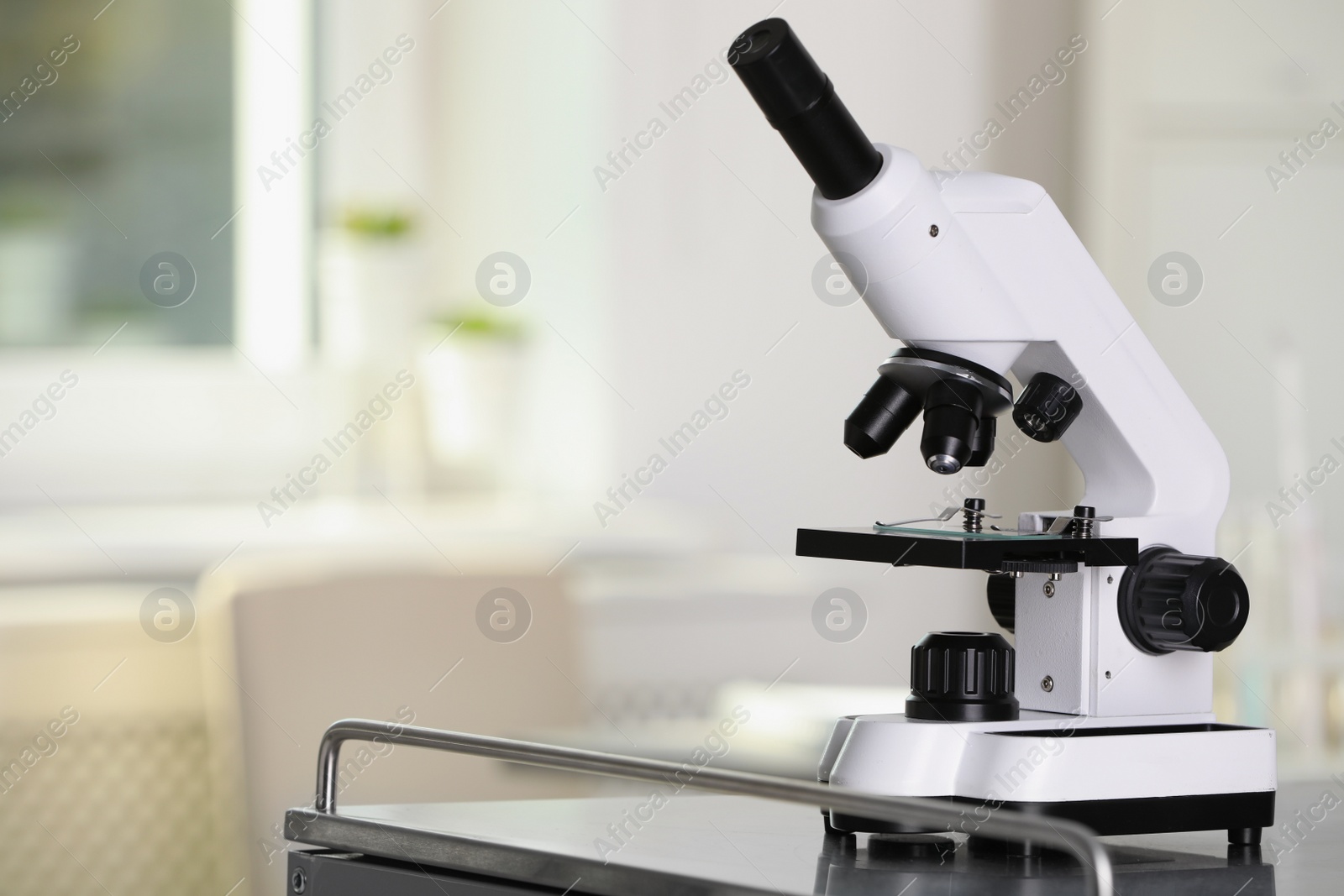 Photo of Modern medical microscope on metal table in laboratory, space for text