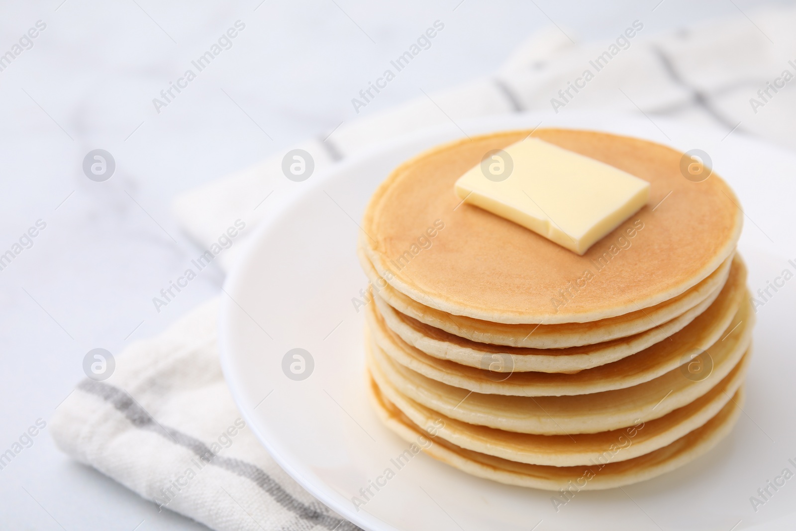 Photo of Delicious pancakes with butter on table, closeup. Space for text