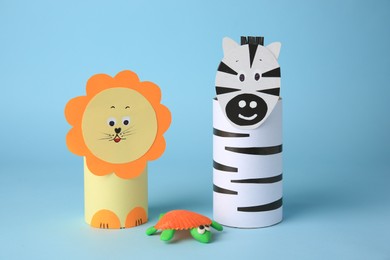 Toy lion, zebra made from toilet paper hubs and plasticine turtle on light blue background. Children's handmade ideas