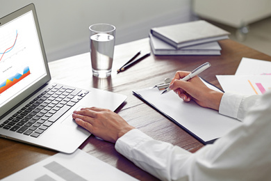 Man working at table in office, closeup. Business analytics