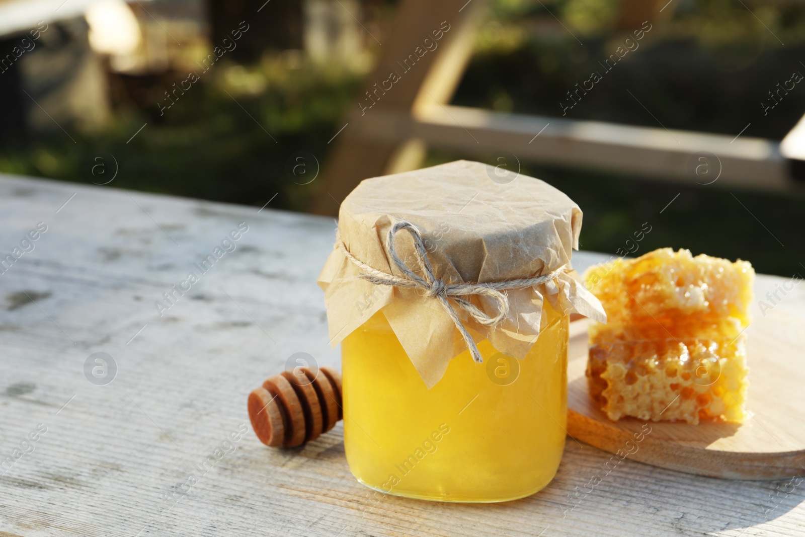 Photo of Fresh aromatic honey and combs on grey wooden table outdoors. Space for text