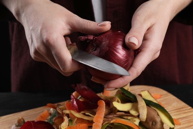 Photo of Woman peeling fresh onion with knife at table, closeup