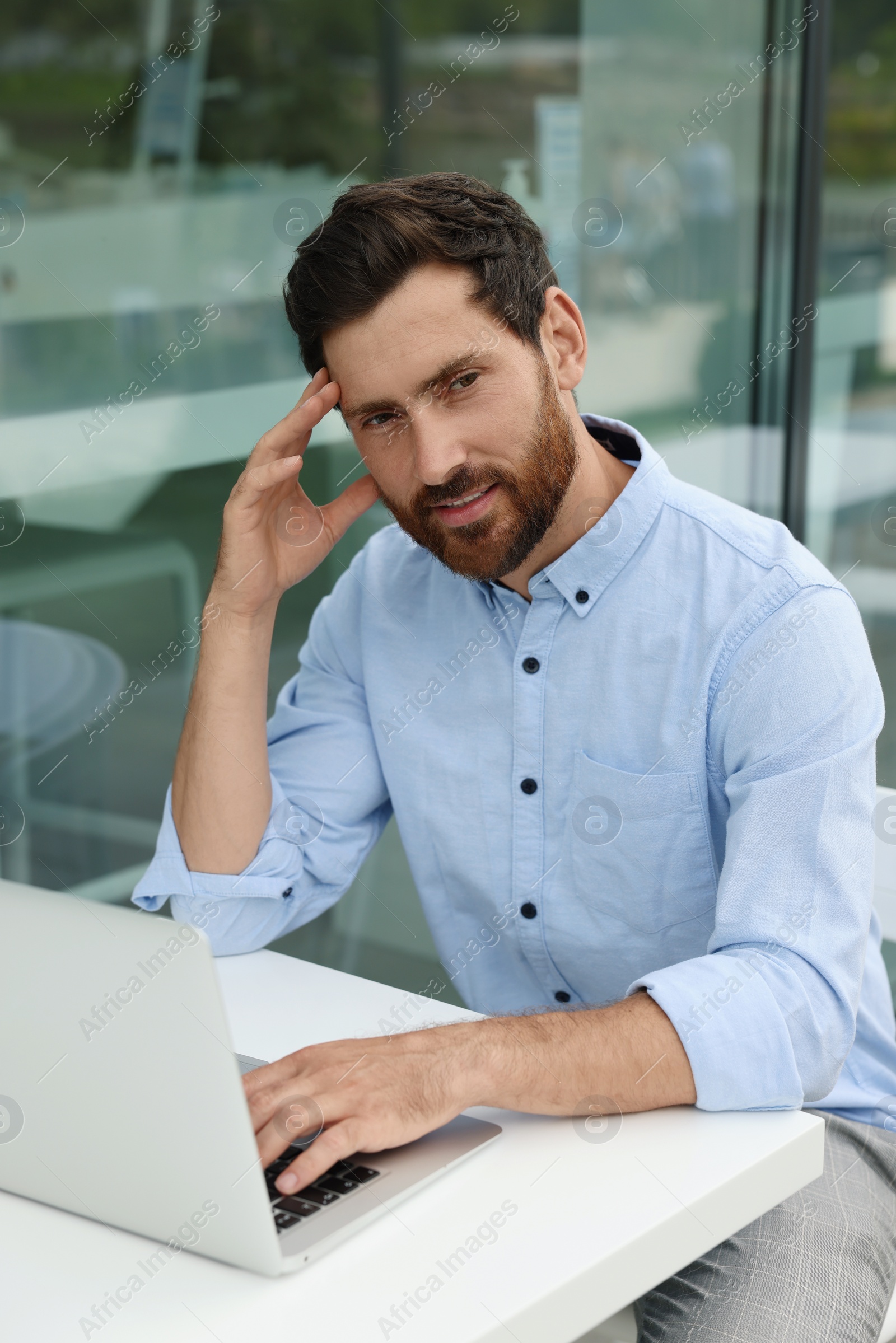 Photo of Portrait of handsome bearded man with laptop in outdoor cafe