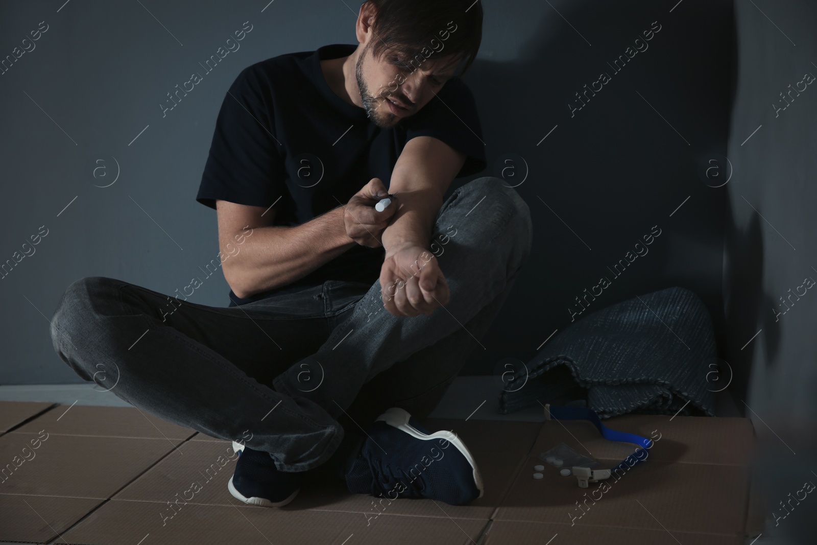 Photo of Male drug addict making injection near grey wall