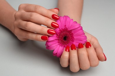 Photo of Woman with red polish on nails touching flower on white background, closeup