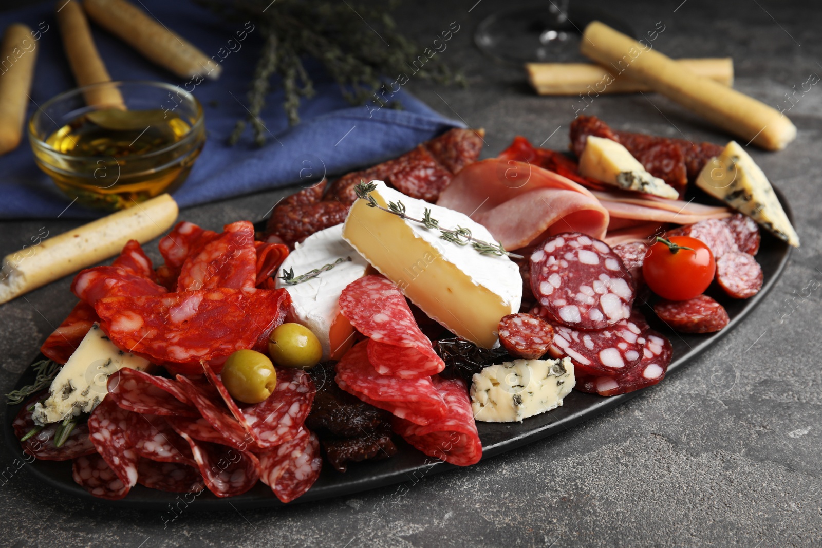 Photo of Tasty ham with other delicacies served on grey table