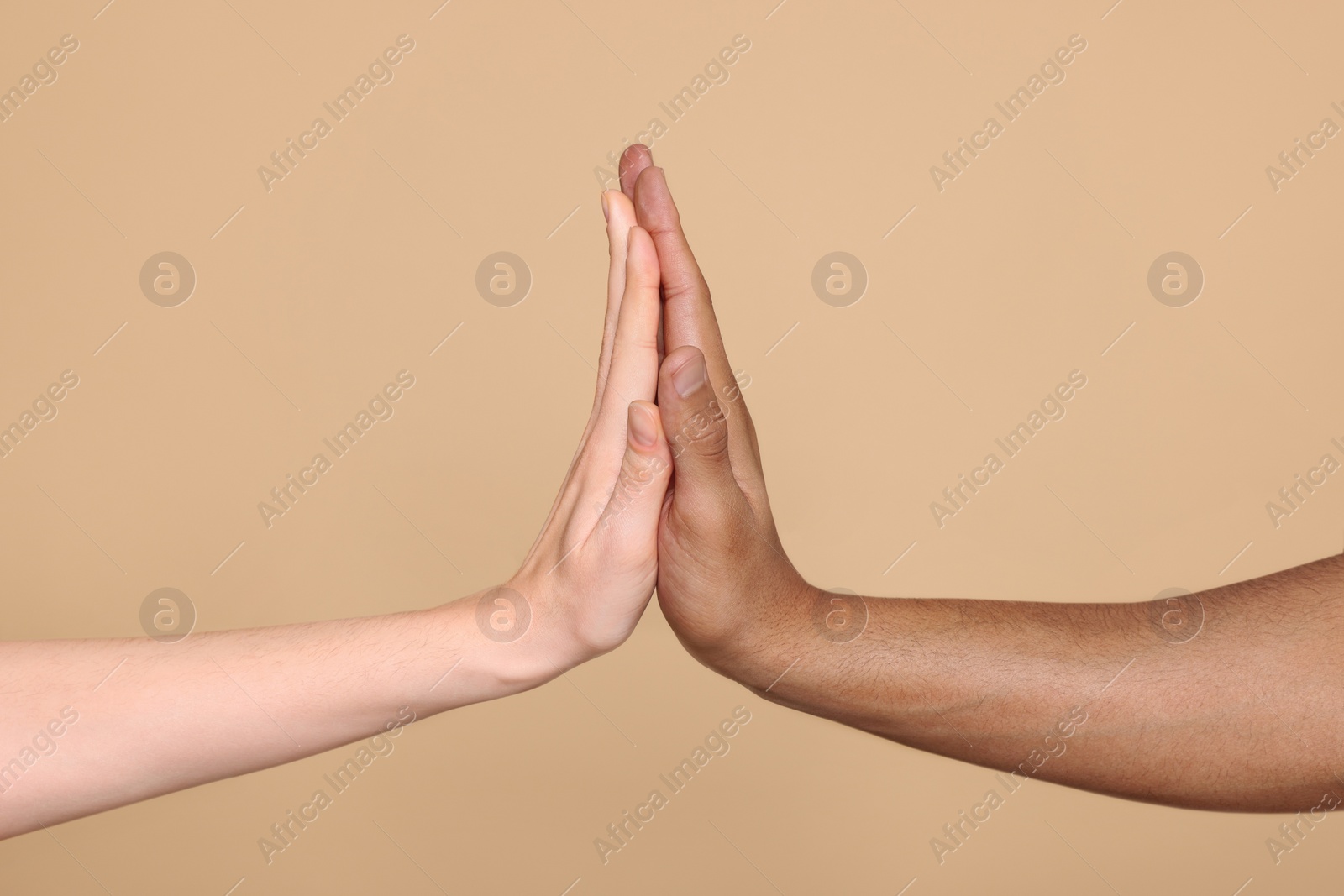 Photo of International relationships. People giving high five on light brown background, closeup