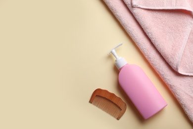 Photo of Bottle with shampoo, towel and comb on color background, flat lay. Space for text