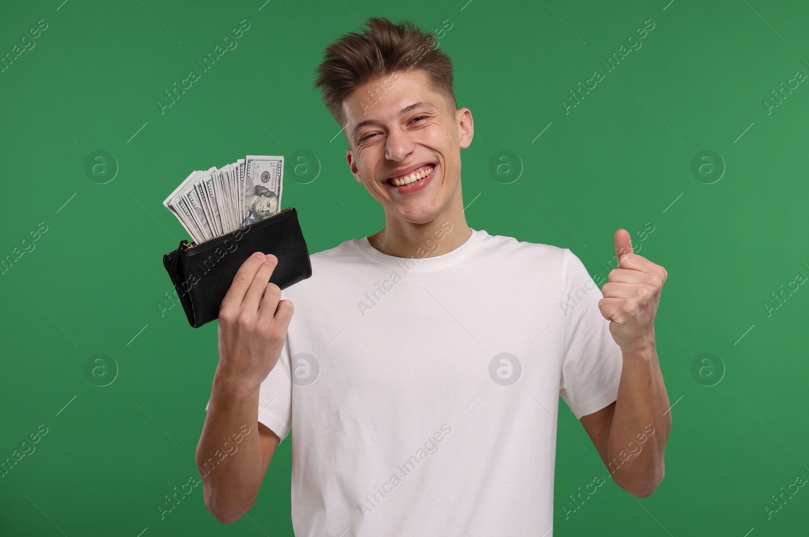 Photo of Happy man with wallet and dollar banknotes on green background