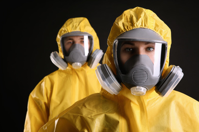 Photo of Man and woman wearing chemical protective suits on black background. Virus research