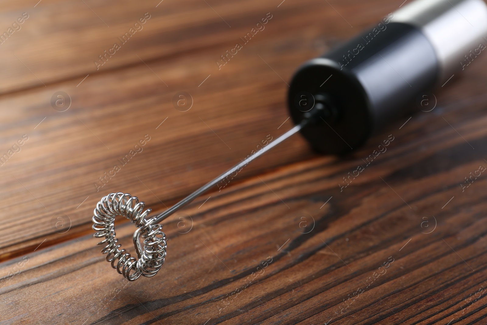 Photo of Black milk frother wand on wooden table, closeup