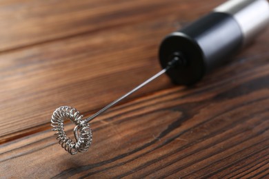 Photo of Black milk frother wand on wooden table, closeup